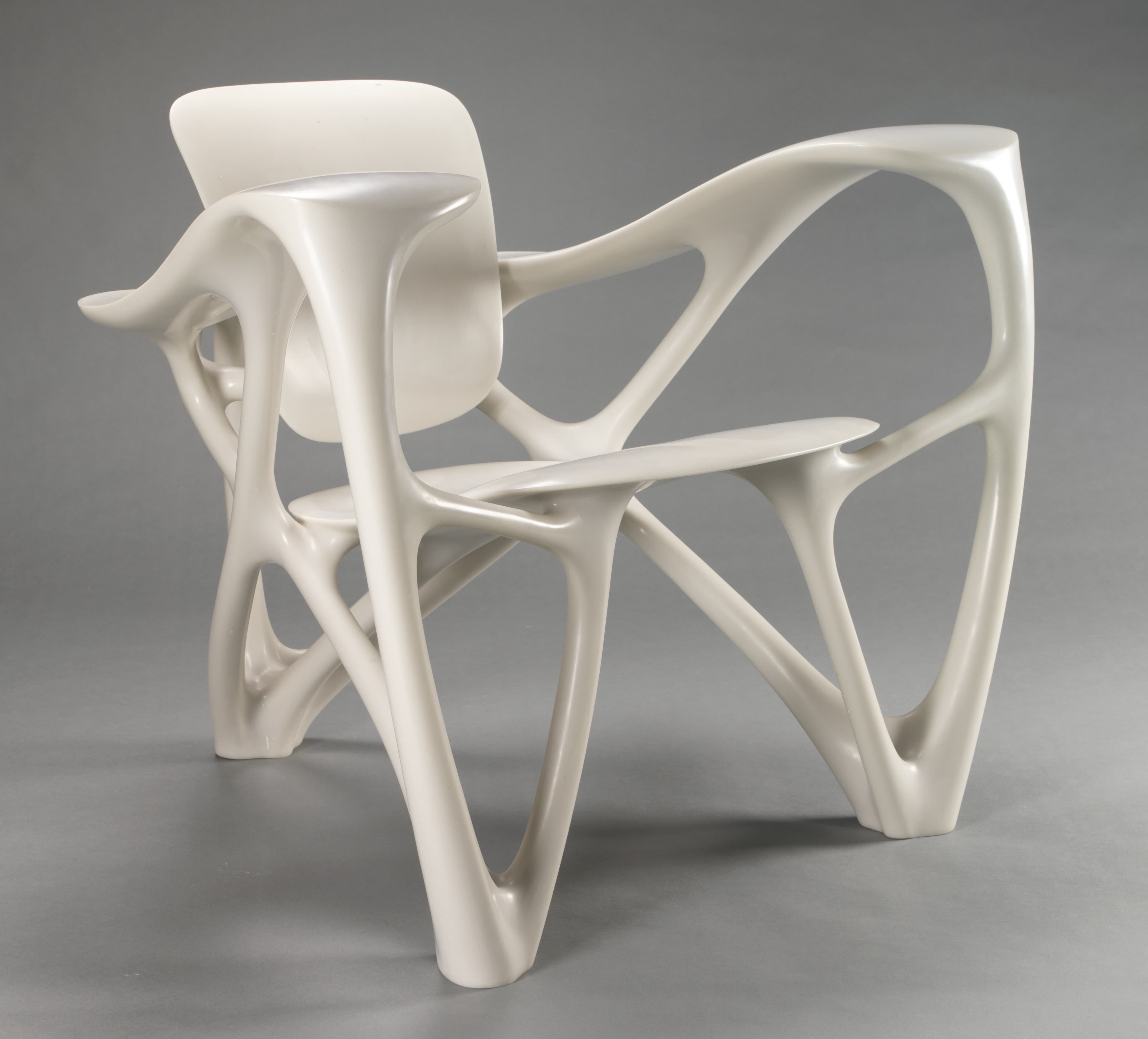 An ivory-white armchair with a space between the back and the seat. The arms and legs of the chair resemble bones connecting everything together.