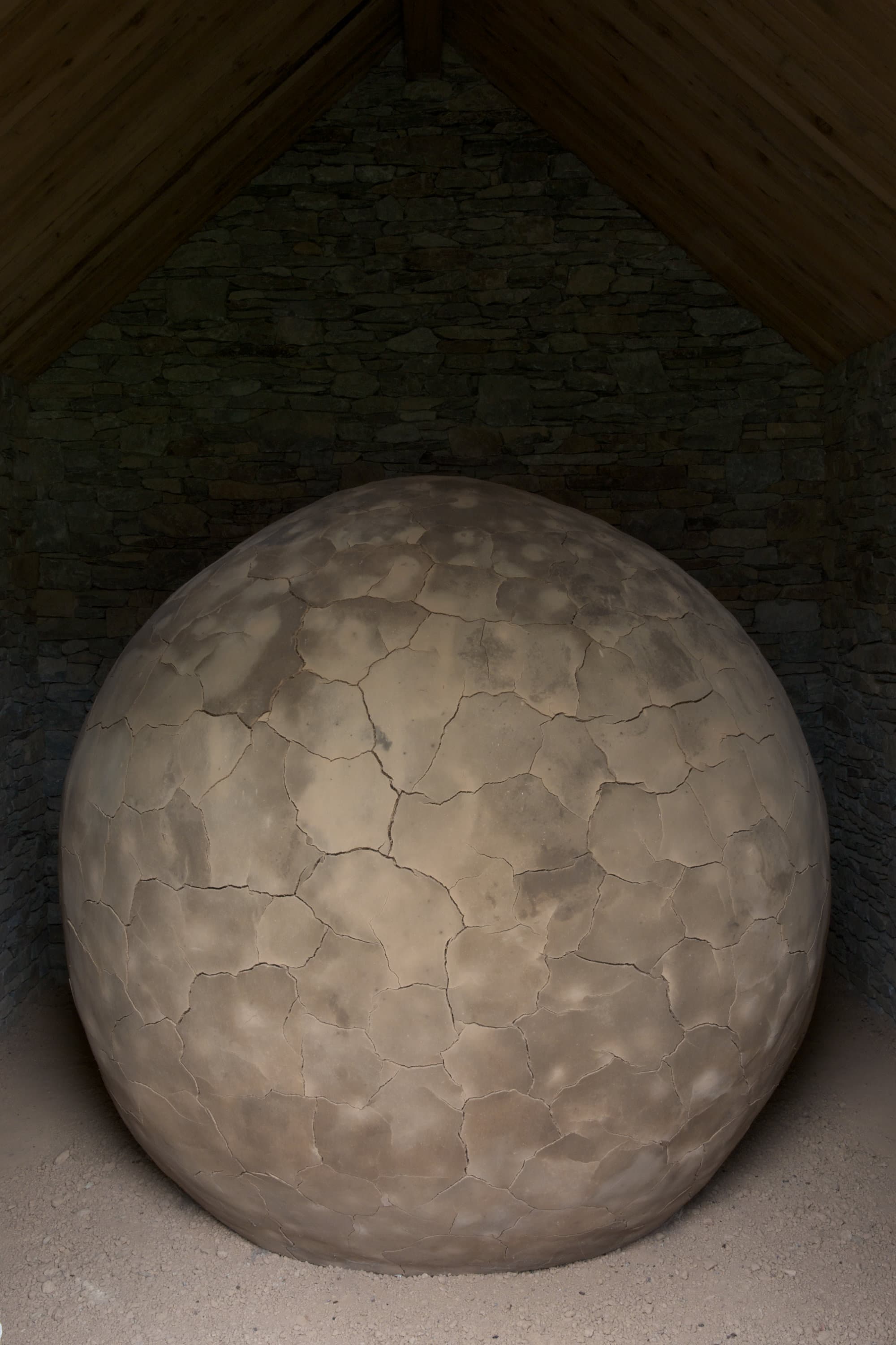 A large clay sphere with cracks running like veins over the surface.