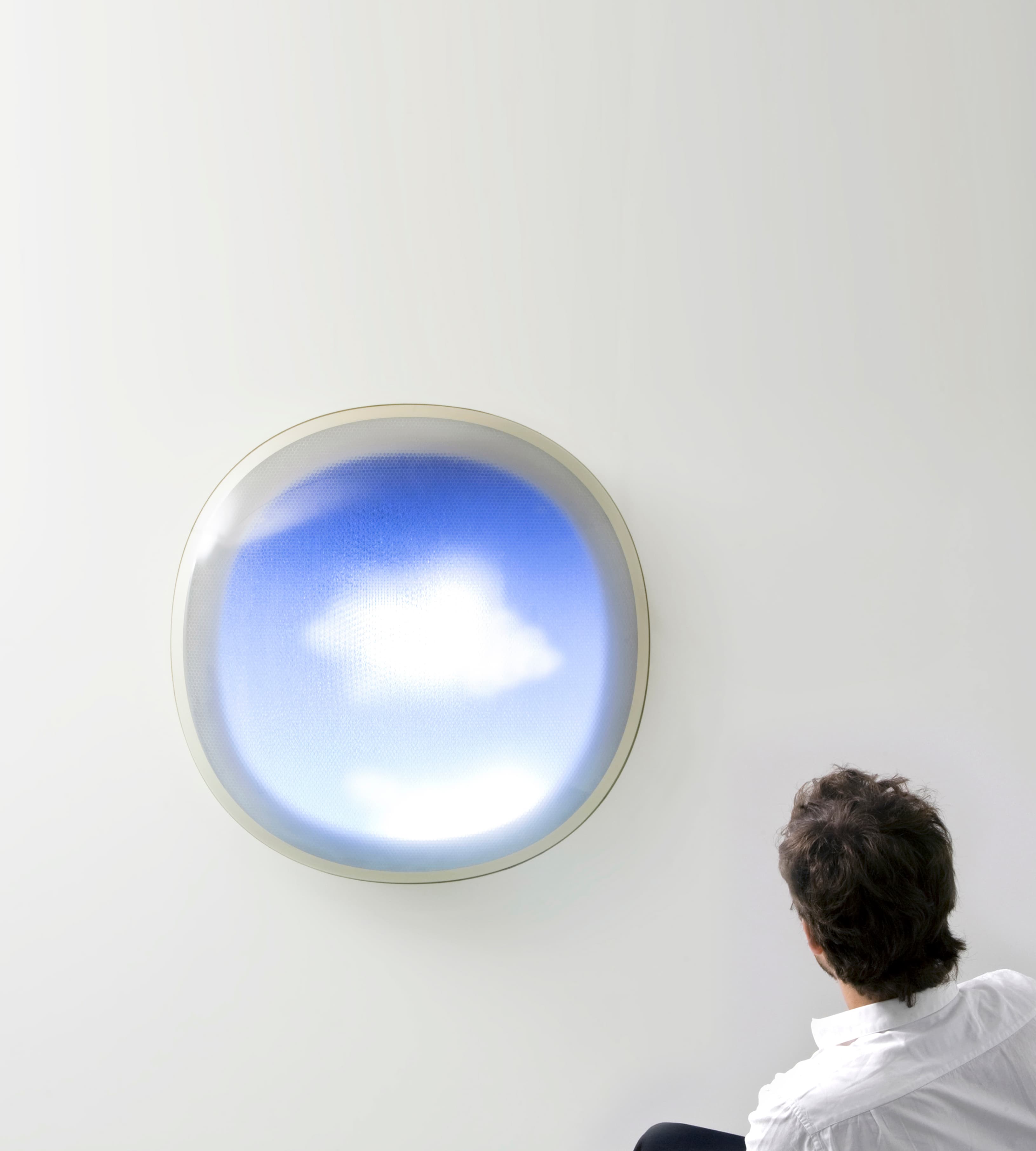 Image of Tomorrow is Another Day, which looks like an airplane window with a bright blue sky and two clouds. In the lower righthand corner, the back of a person’s head and shoulders as they look at the artwork.